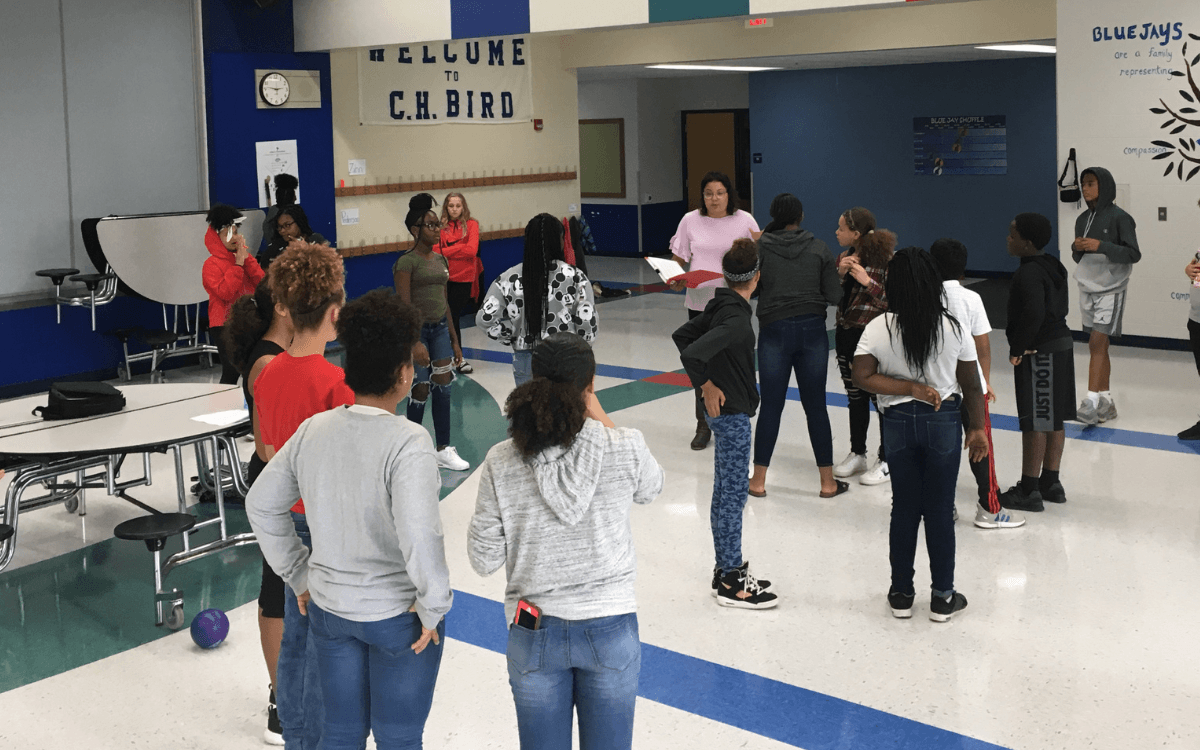 A group of teens stand in a circle participating in an interactive activity